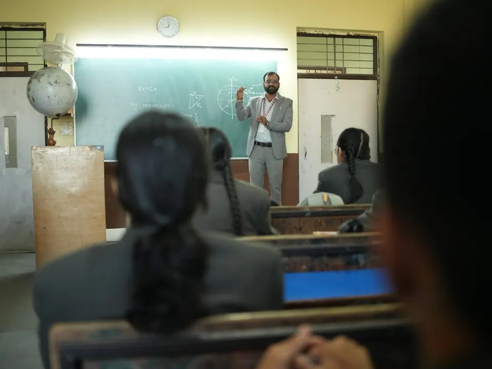 Students in blazers listen to a lecture in a classroom