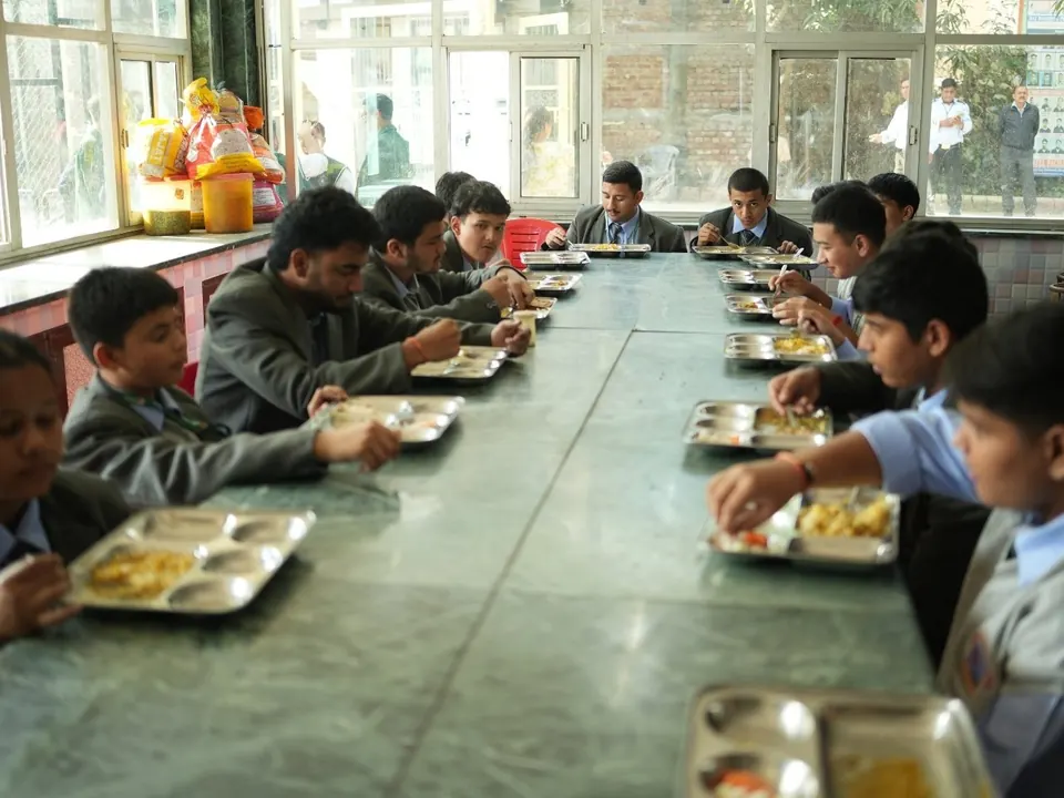 Students eat a meal together at a long table in the dining hall