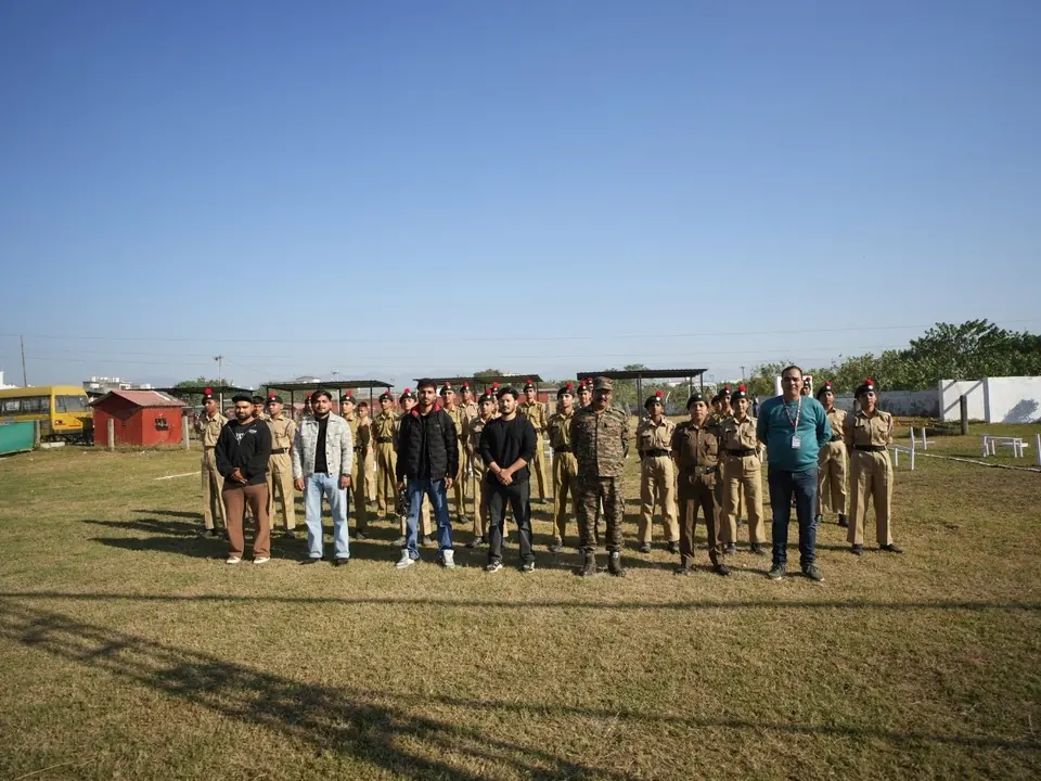 Students and staff stand in rows on the ground for an assembly