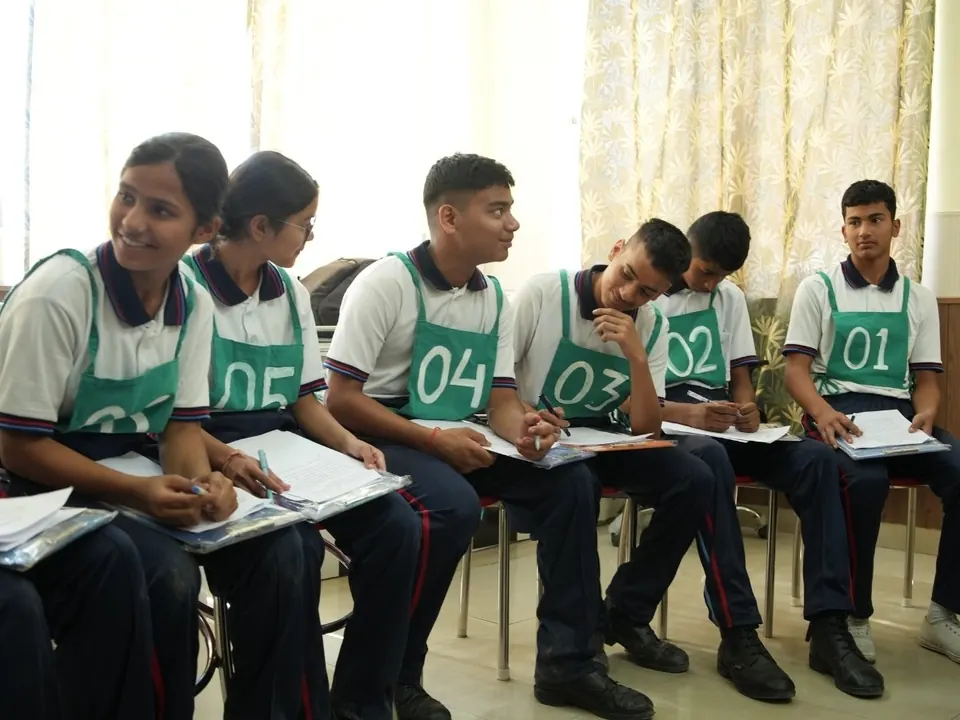 Students with numbered bibs take notes and talk during a group exercise