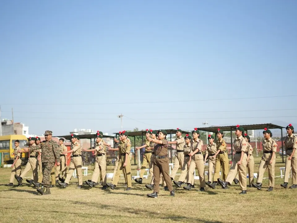 Students in uniform follow an instructor through a physical training drill outdoors