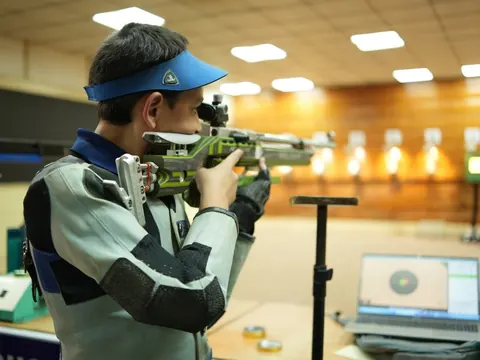 A student aims a rifle at an indoor shooting range