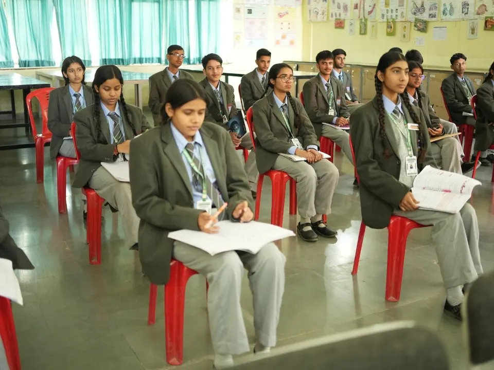Students in blazers sit with papers during a written session